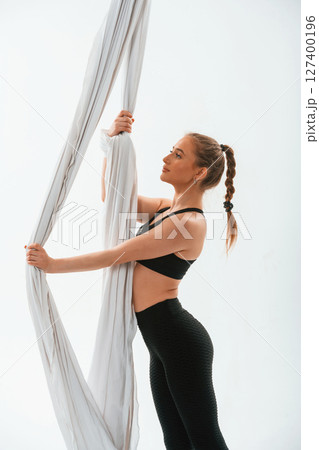 Holds the canvas. Young beautiful woman doing fly yoga against white background Holds the canvas. Young beautiful woman doing fly yoga against white background 127400196