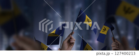 Barbados flags in their hands on a blurred urban background Barbados flags in their hands on a blurred urban background 127400213