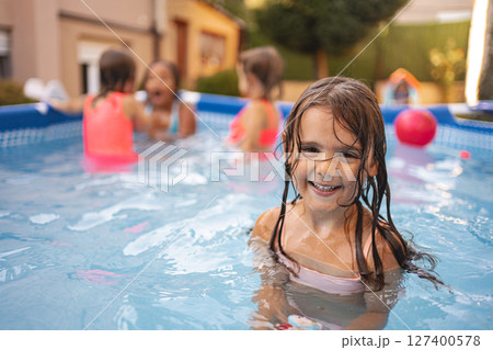 Girl joyfully plays in a pool with friends 127400578