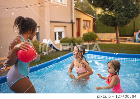 Children enjoying a playful afternoon in an inflatable pool 127400584
