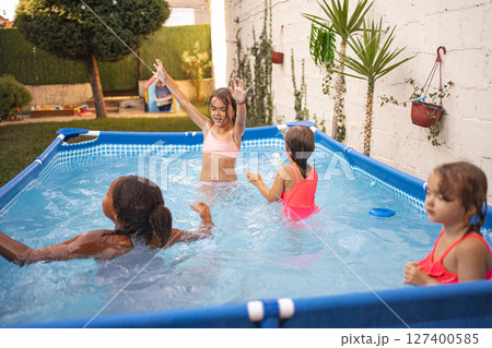 Girls playing and enjoying a sunny afternoon in a backyard pool 127400585