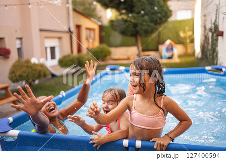 Children playing and splashing in pool during summer afternoon fun 127400594
