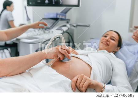 Smiling, medical procedure. Pregnant woman is lying down in the hospital, doctor does ultrasound Smiling, medical procedure. Pregnant woman is lying down in the hospital, doctor does ultrasound 127400698