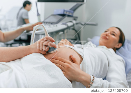 Pregnant woman is lying down in the hospital, doctor does ultrasound 127400700