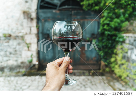 Red Wine Glass in Hand with Stone Cellar Background in France or Italy 127401587