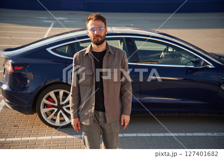In glasses. Man is standing near his electric car outdoors 127401682