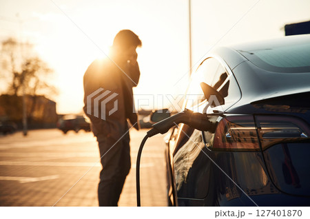Waiting for the automobile to charge. Man is standing near his electric car outdoors 127401870