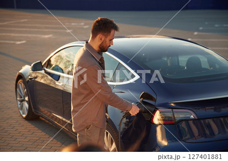 Time to charge the automobile. Man is standing near his electric car outdoors 127401881