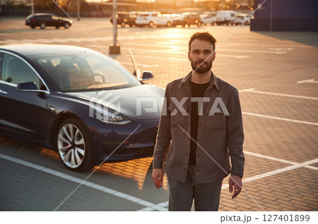 Handsome man is standing near his electric car outdoors 127401899