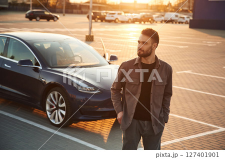 Handsome man is standing near his electric car outdoors 127401901