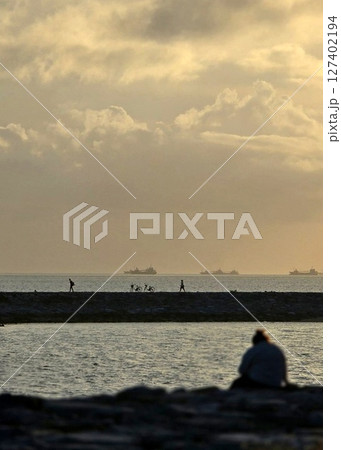 夕暮れの海を見つめる人々の静かな時間（縦構図） 127402194