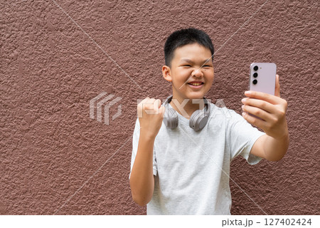 Teenager Boy Portrait Against Plain Wall in Natural Light 127402424