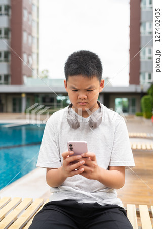 Teenage Boy at Poolside During Summer Using Phone Teenage Boy at Poolside During Summer Using Phone 127402435