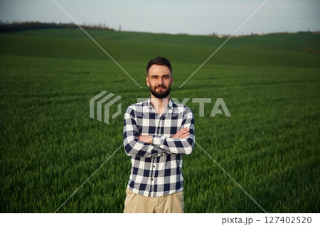 Standing with arms crossed. Handsome young man is on agricultural field Standing with arms crossed. Handsome young man is on agricultural field 127402520