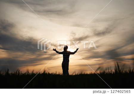 Silhouette of a man that is in the field at sunset time. Dramatic sky Silhouette of a man that is in the field at sunset time. Dramatic sky 127402565