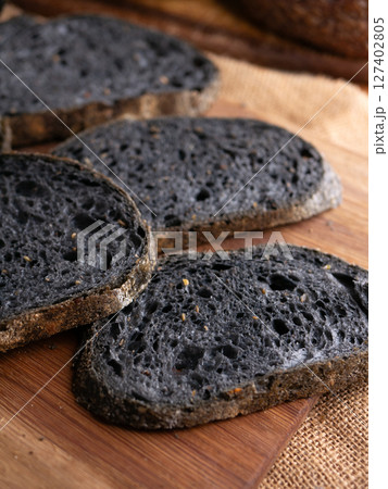 Fresh baked black charcoal sourdough ciabatta bread sliced on wooden board. Fresh baked black charcoal sourdough ciabatta bread sliced on wooden board. 127402805