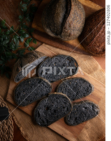 Fresh baked black charcoal sourdough ciabatta bread sliced on wooden board. 127402806