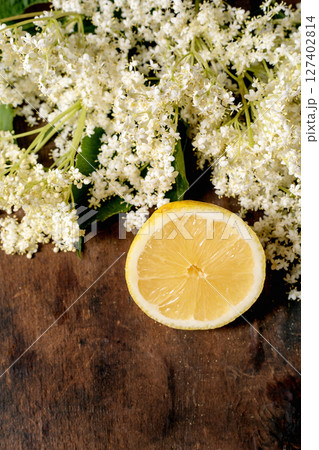 Fresh elderflower clusters with lemon slice on wooden background. Natural ingredients for homemade syrup tea traditional recipes Fresh elderflower clusters with lemon slice on wooden background. Natural ingredients for homemade syrup tea traditional recipes 127402814