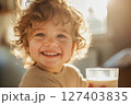 Smiling child in morning sun with glass of milk 127403835