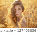 Portrait of young woman in sunset sun at ripe wheat field 127403836