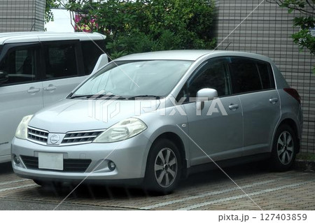 駐車場に並んだ乗用車(日産・ティーダ 初代 ) 127403859