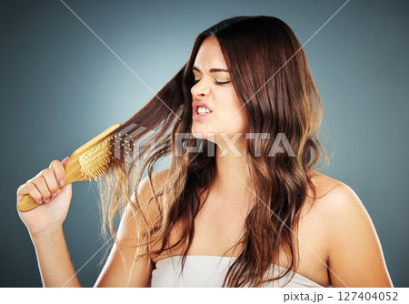 Hair care, brush and frustrated woman brushing damaged and tangled hair on a gradient studio background. Female model with crisis, stress and disaster with hair loss problem with hairdresser shampoo Hair care, brush and frustrated woman brushing damaged and tangled hair on a gradient studio background. Female model with crisis, stress and disaster with hair loss problem with hairdresser shampoo 127404052