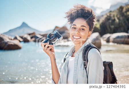 Travel, beach and camera with a black woman tourist taking a photograph by the sea or ocean water in summer. Nature, portrait or photographer with a female outdoor on holiday or vacation by the coast Travel, beach and camera with a black woman tourist taking a photograph by the sea or ocean water in summer. Nature, portrait or photographer with a female outdoor on holiday or vacation by the coast 127404391