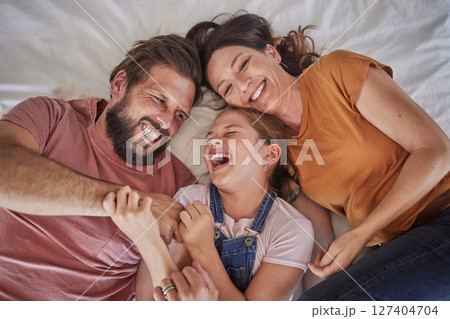 Family, bed and child with tickle, happy or comic play for quality time, bonding or home together. Above, parents and girl with happiness, laugh or crazy with love, mom and dad in happy family house 127404704