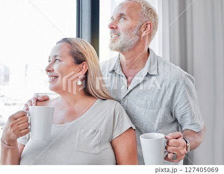 Elderly couple, hug and coffee by window with smile in contemplation, vision or morning routine at home. Happy senior man and woman smiling looking out glass while enjoying a warm drink together Elderly couple, hug and coffee by window with smile in contemplation, vision or morning routine at home. Happy senior man and woman smiling looking out glass while enjoying a warm drink together 127405069