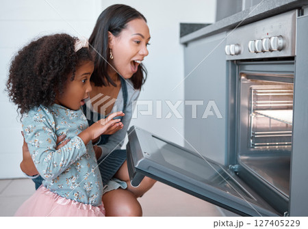 Kitchen, mom and girl excited with baking in oven, checking results, working together and learning to bake family recipe. Child development, happy home cooking and bonding time for woman and child 127405229