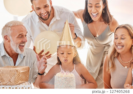 Birthday cake, blow candle and family celebration, party and singing with decorations, event and gift in home. Happy birthday, birthday party or candles for girl with parents, grandparents or balloon 127405268