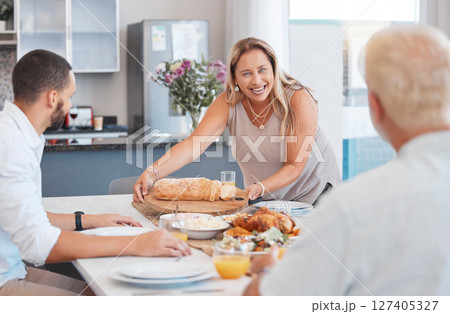 Lunch, celebration and happy family with food at a dining room table on holiday at the accommodation. Serving, dinner and senior woman with bread and chicken for hungry people in family home 127405327