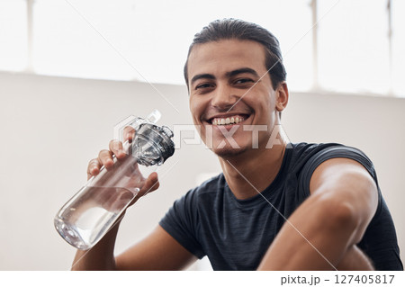 Fitness, water bottle and portrait of a man on a break after an intense workout or training in the gym. Sports, rest and happy athlete drinking a beverage while resting after exercise in sport center 127405817