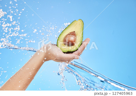 Hand, water and avocado for beauty splash and organic skincare product on a blue studio background. Avo, vegetable and natural produce for bodycare, skin care and nutrition or healthy diet 127405963