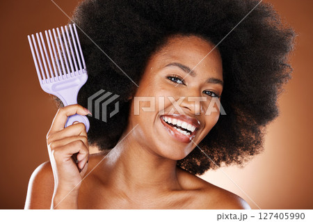 Happy black woman, hair care and comb in portrait with afro pick, beauty and self care by brown backdrop. African woman, model and cosmetics with makeup or happiness for combing by studio background 127405990