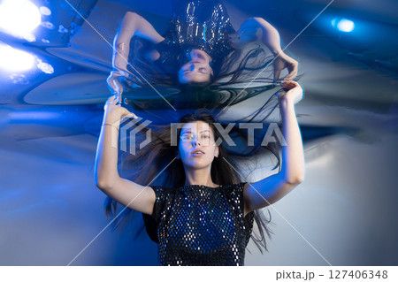 Girl With Long Hair Resembling a Mermaid Under Shimmering Blue Lights Girl With Long Hair Resembling a Mermaid Under Shimmering Blue Lights 127406348