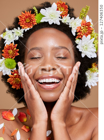 Flowers, beauty and black woman with smile, happy and skincare plants in brown studio background. Spring, healthy skin and nature girl model with flower, face and advertising facial cosmetic product 127406350