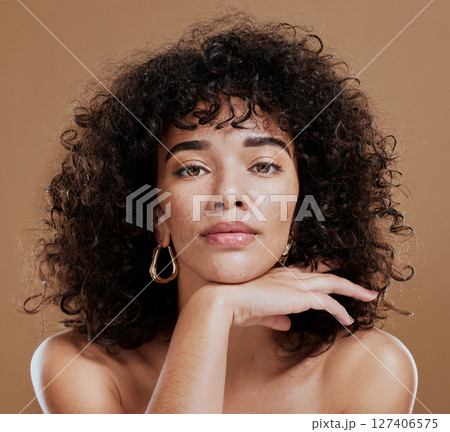 Makeup, confident and portrait of a woman with hair care, skincare and beauty against a brown studio background. Face, cosmetic and young girl model with a curly afro, cosmetics and empowerment 127406575