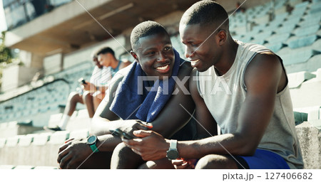 Sports, stadium and athlete friends with phone, smile and checking online schedule at team practice together. Relax, smartphone and men in bleachers for fitness app, progress tracking or workout plan 127406682