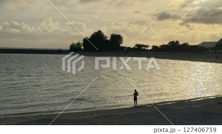 海辺に立つ人物のシルエットと夕暮れの金色の波(横構図) 海辺に立つ人物のシルエットと夕暮れの金色の波(横構図) 127406759