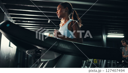 Runner, gym and health with woman on treadmill for training, exercise and cardio performance. Wellness, fitness and workout challenge with person on running machine for sports, athlete and low angle 127407494