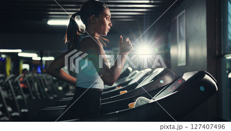 Exercise, girl and running on treadmill in gym at night for agility training, speed development or calorie burning. Flare, evening workout or woman on machine for cardio fitness or muscle performance 127407496