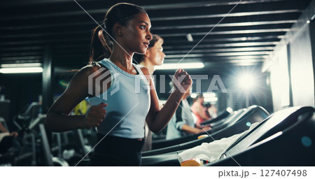 Fitness, girl and running on treadmill in gym at night for agility training, endurance challenge or burning calories. Sweating, late exercise and runner with speed for intense cardio or race practice Fitness, girl and running on treadmill in gym at night for agility training, endurance challenge or burning calories. Sweating, late exercise and runner with speed for intense cardio or race practice 127407498