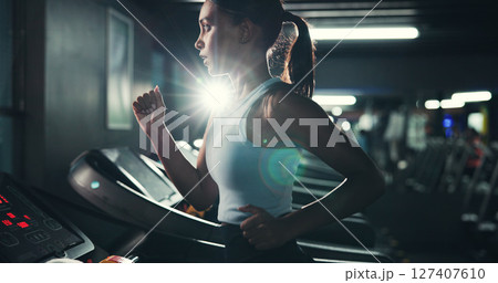 Fitness, woman and running on treadmill in gym at night for agility training, speed development or calorie burning. Flare, evening workout or girl on machine for cardio exercise or muscle performance Fitness, woman and running on treadmill in gym at night for agility training, speed development or calorie burning. Flare, evening workout or girl on machine for cardio exercise or muscle performance 127407610