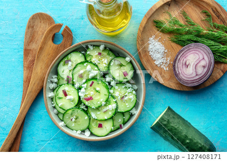 Cucumber salad with dill, red onion, and goat cheese, on a blue background Cucumber salad with dill, red onion, and goat cheese, on a blue background 127408171