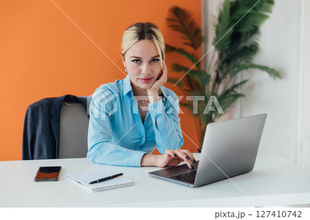 Blonde businesswoman working with laptop online at desk in office Blonde businesswoman working with laptop online at desk in office 127410742