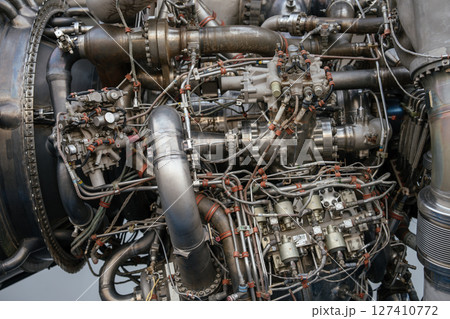 Extreme close-up view of the rocket engine showing intricate wiring, pipes, and control modules. The image highlights the complex engineering of a spacecraft propulsion system. 127410772
