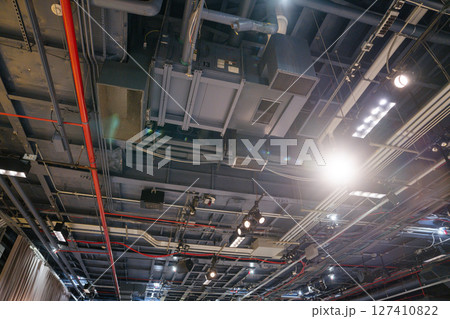 Close-up view of an industrial ceiling with exposed ducts, pipes, and lighting fixtures. The image captures the technical infrastructure inside the Intrepid Museum exhibition space. 127410822