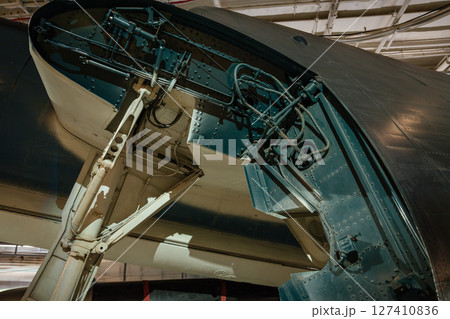 Detailed view of the landing gear and hydraulic systems inside a military aircraft's wheel well. The image shows mechanical components, cables, and structural elements. 127410836
