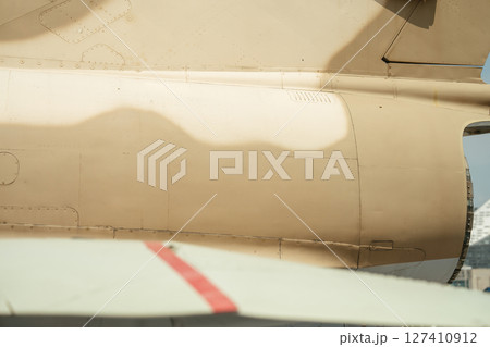 A detailed view of the rear section of a camouflage-painted military aircraft. The image highlights panel lines, rivets, and soft shadows across the aircraft body. 127410912